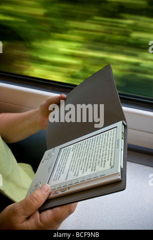 Sony eReader tragbare elektronische eBook-Lesegerät, Hände halten, in Zugwagen mit Bewegungsgeschwindigkeit verschwommen Hintergrund Stockfoto