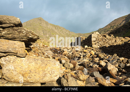 Snowdon im frühen Morgenlicht mit Afon Glaslyn im Vordergrund wie es auf den Bergmann über Felsbrocken in der Nähe von Glaslyn stürzt Stockfoto
