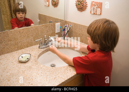 ein sieben Jahre alter Junge, der seine Händewaschen mit Seife in das Waschbecken im Badezimmer zu Hause Stockfoto