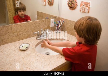 ein sieben Jahre alter Junge, der seine Händewaschen mit Seife in das Waschbecken im Badezimmer zu Hause Stockfoto