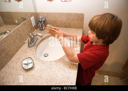 ein sieben Jahre alter Junge, der seine Händewaschen mit Seife in das Waschbecken im Badezimmer zu Hause Stockfoto