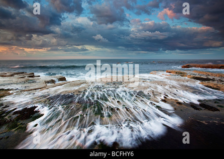 Brechende Welle bei Sonnenuntergang gegen Bay in der Nähe von Whitby North Yorkshire Coast Stockfoto