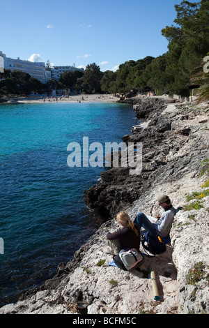 Mann und Frau lesen, sitzen auf den Felsen an der Bucht Cala d ' or Mallorca Spanien Stockfoto