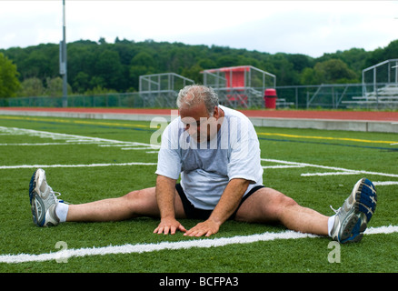 Mittleres Alter senior woman Dehnung seiner Muskeln nach dem Training am Sportplatz mit Übergewicht Stockfoto