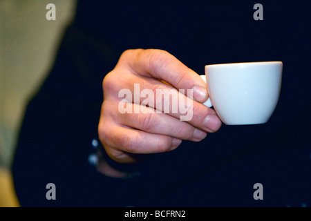 Profil von ein glatzköpfiger Mann in seiner späten 40 trägt einen dunklen Anzug, einen Espressokaffee zu trinken. Stockfoto