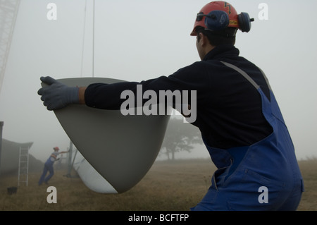 Arbeiter bewegen ein Rotorblatt, um es am Rotorkörper einer Windenergieanlage zu befestigen. Alberona, Italien. Stockfoto