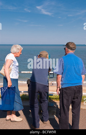 Touristen auf der Suche durch die Bezahlung Fernglas auf Southwold Strandpromenade in Großbritannien anzeigen Stockfoto