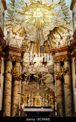Karlskirche Hochaltar Apotheose des hl. Karl Borromäus Wien | WIEN, Österreich — Eine Stuckfigur des hl. Karl Borromäus von Alberto Camesina steigt zu einem goldenen Sonnenaufgang auf, der den Tetragrammaton am Hochaltar der Karlskirche umrahmt. Johann Bernhard Fischer von Erlach entwarf die Altarkomposition mit goldenen Engeln und einem von Lorenzo Mattielli hinzugefügten Kruzifix. Kaiser Karl VI. Baute die Kirche, um ein Pestgelübde von 1713 zu erfüllen, und der Entwurf des Altars stellt Borromeo, einen heiligen, der für die Betreuung der Pestopfer Mailands verehrt wird, in den Mittelpunkt dieses Gründungsziels. Stockfoto