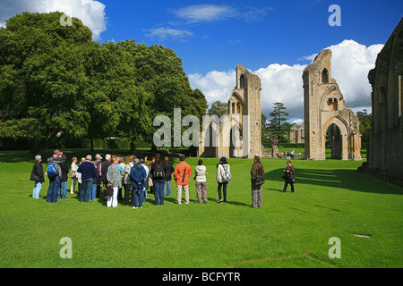 Eine Gruppe von Besuchern bekommen eine Führung von Glastonbury Abbey Ruinen, Somerset, England, UK Stockfoto