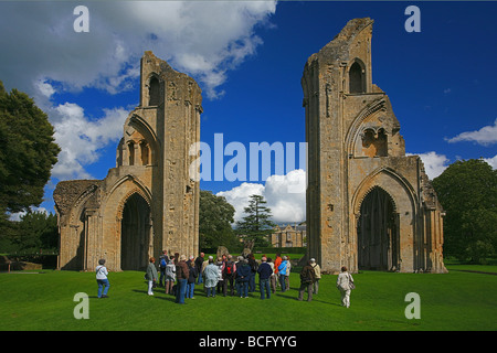 Eine Gruppe von Besuchern bekommen eine Führung von Glastonbury Abbey Ruinen, Somerset, England, UK Stockfoto