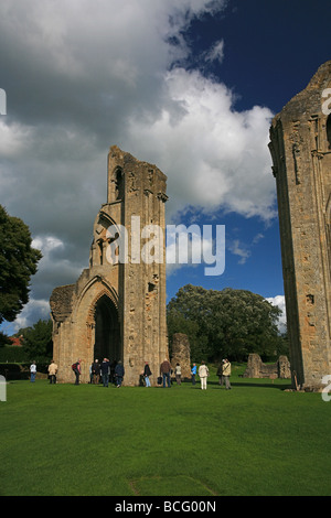 Eine Gruppe von Besuchern bekommen eine Führung von Glastonbury Abbey Ruinen, Somerset, England, UK Stockfoto