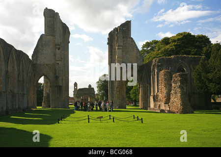 Eine Gruppe von Besuchern bekommen eine Führung von Glastonbury Abbey Ruinen, Somerset, England, UK Stockfoto