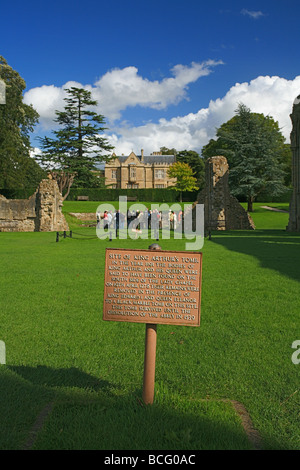 Eine Gruppe von Besuchern bekommen eine Führung von Glastonbury Abbey Ruinen auf dem Gelände des König Arthurs Grab, Somerset, England, UK Stockfoto