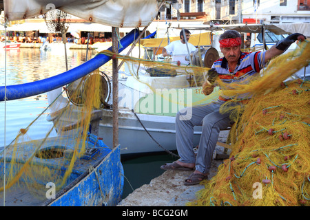 Ein Fischer seine Netze im venezianischen Hafen von Rethymnon Kreta Griechenland mit den Tavernen direkt am Meer hinter ihm vorbereiten Stockfoto