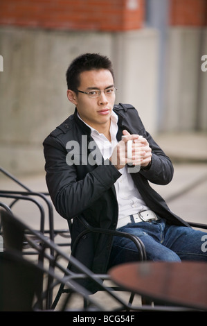 Junger asiatischer Mann bei einer Tasse Kaffee im freien Stockfoto