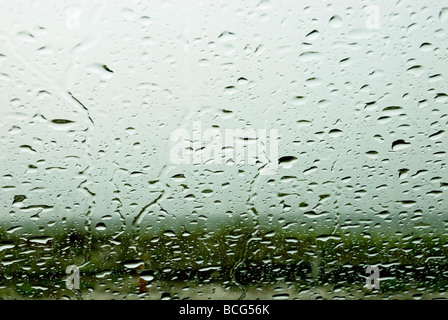 Regentropfen durch ein Autofenster Stockfoto