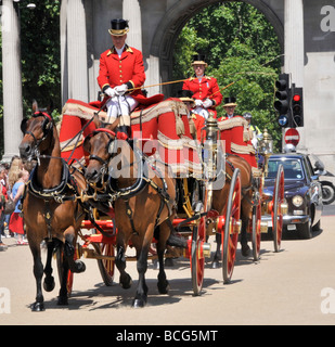 Zwei Pferdekutschen mit Begleitung eines Fahrzeugs, die durch eine Bogenwand fahren und an einem warmen, sonnigen Juni-Tag in London, England, Großbritannien, in den Royal Hyde Park einfahren Stockfoto