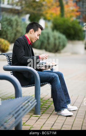 Junge asiatische Mann einen Sushi Lunch im Freien genießen Stockfoto