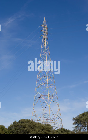 Strommast vor blauem Himmel mit Wolkenfetzen Stockfoto