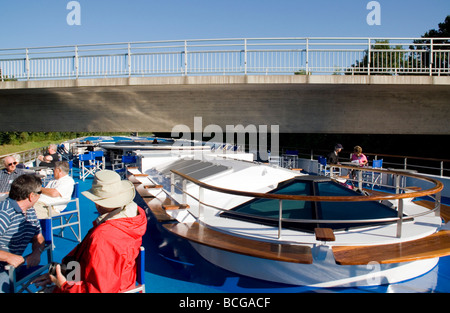 Kreuzfahrt-Passagiere auf Observation Deck beobachten Schiff mit Radhaus unten deutlich niedrige Brücke am Main-Kanal in Deutschland Stockfoto