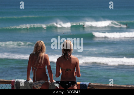 Zwei attraktive junge Frauen in Bikinis beobachten das Surfen in Yallingup in Geographe Bay Western Australia Stockfoto