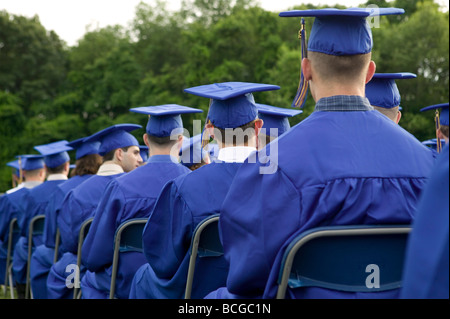 Schülerinnen und Schüler tragen blaue und goldene Mütze und Mantel besuchen Abschlussfeier in USA Stockfoto