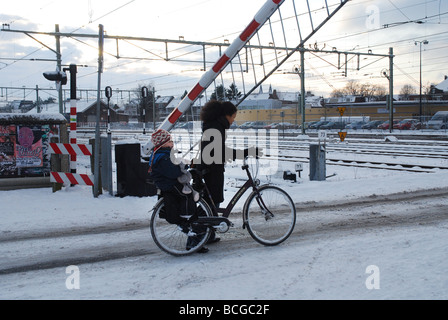 Radfahrer am Bahnübergang im Winter warten Stockfoto