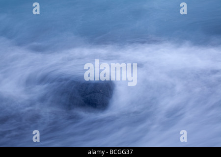 Meer, die Felsen am Strand mit der steigenden Flut herumwirbeln Stockfoto