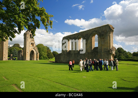 Eine Gruppe von Besuchern bekommen eine Führung von Glastonbury Abbey Ruinen, Somerset, England, UK Stockfoto