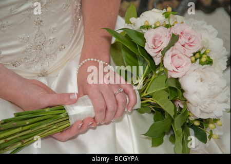 Braut hält Blumenstrauss in Runde mit Ehering Stockfoto