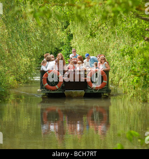 Familien genießen eine Bootsfahrt entlang einer Weide, von Bäumen gesäumten Fluss. Groombridge Place, Kent, England, UK Stockfoto