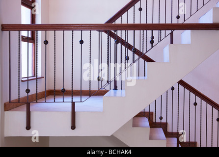 Moderne Treppe mit schmiedeeisernen Geländer und Handlauf aus Holz. Stockfoto