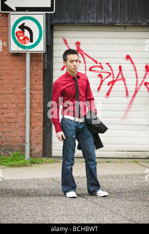 Junge asiatische Mann in einer Graffitied-Gasse Stockfoto