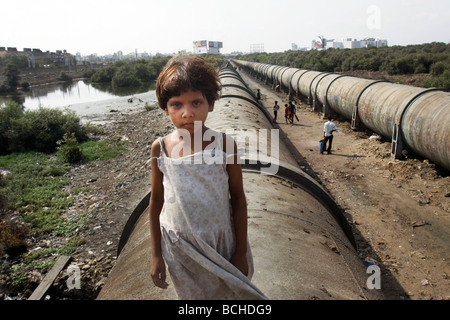 Ein armes Mädchen steht auf eine Wasserleitung, die durch Dharavi, der größte Bereich der Slum in Mumbai (Bombay) in Indien läuft Stockfoto