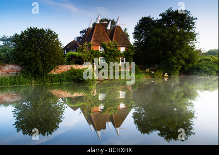 Kentish Oast House auf den Fluss Medway mit frühen Morgen gespiegelt Reflexionen. Stockfoto