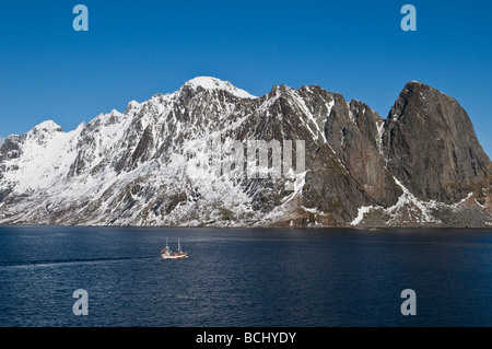 Dorsch Angeln Boot Segeln in den Gewässern des Kjerkfjorden mit Schnee bedeckt die Berge im Hintergrund in der Nähe von Reine, Lofoten Inseln, Norwegen Stockfoto