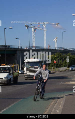 Ein Radfahrer mit Kräne im Hintergrund. London. VEREINIGTES KÖNIGREICH. Stockfoto