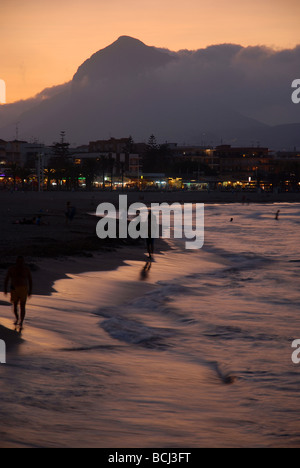 Touristen auf den Arenal Strand mit Sonnenuntergang hinter Montgo Javea / Xabia, Provinz Alicante, Comunidad Valenciana, Spanien Stockfoto