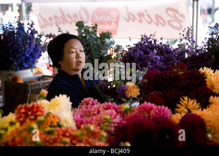 Reife Asiatin bietet Blumen am Pike Place Market Seattle Stockfoto