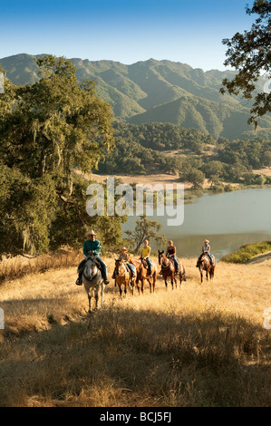 Reiter auf Hügel bedeckt mit Rasen und Eichen, mit Blick auf See Alisal Alisal Ranch in Solvang, Kalifornien, USA. Stockfoto