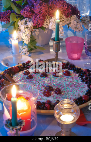 Bunt geschmückten Kirschkuchen auf einem Tisch mit Kerzen in einem gemütlichen Zimmer Stockfoto