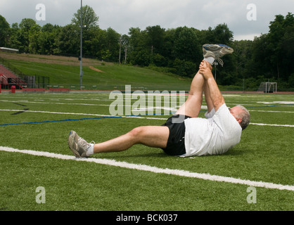 Übergewicht Mittelalter im Ruhestand und aktiven senior woman Dehnung Bein Muskeln nach dem Training auf einem Sport-Bereich im freien Stockfoto