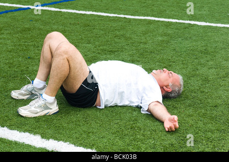 Übergewicht Mittelalter im Ruhestand und aktiven senior woman Dehnung Bein Muskeln nach dem Training auf einem Sport-Bereich im freien Stockfoto