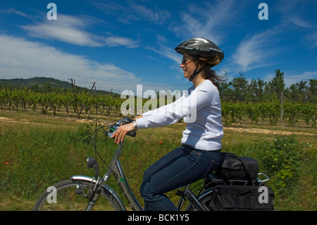 Eine junge Frau fährt ein Elektro-Fahrrad mit einem ruhigen Feldweg der Provence. Frankreich Stockfoto