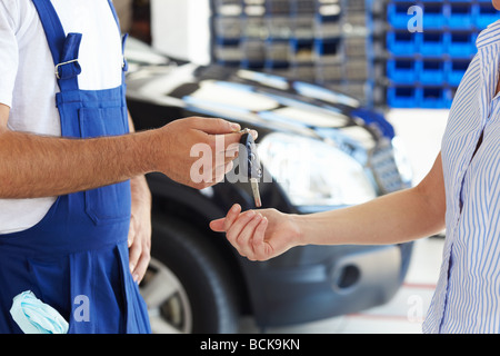 Ansicht der Mechaniker den Autoschlüssel an weibliche Kunden zugeschnitten Stockfoto