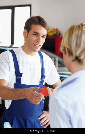 weiblichen Kunden Mechaniker per Kreditkarte zu bezahlen. Stockfoto