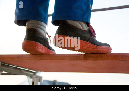 Handwerker in der bluey balancieren auf einem Gerüst Stockfoto