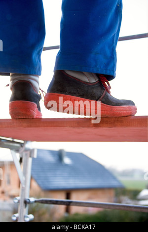 Handwerker in der bluey balancieren auf einem Gerüst Stockfoto