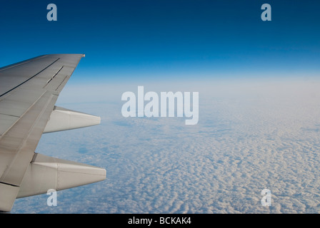 Wunderbare Landschaft von flauschigen Wolken vor einem tiefblauen Himmel mit dem Flügel eines Flugzeuges in der Ecke Stockfoto