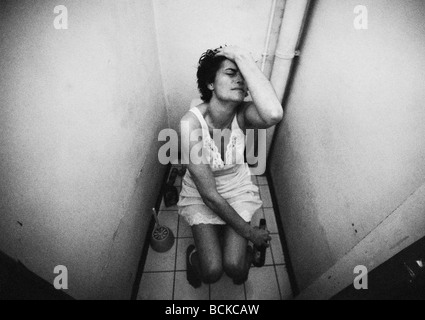 Frau sitzt auf Toilette mit Flasche, b&w Stockfoto